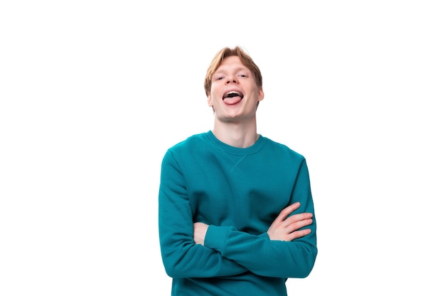 Young handsome redhaired man with a blue sweater laughs on a white background