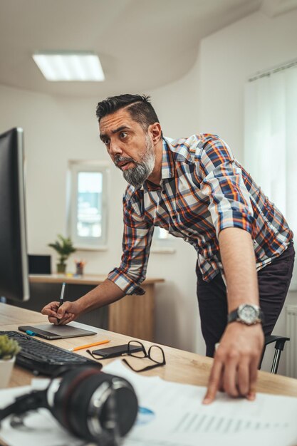 Foto giovane uomo d'affari pensieroso serio bello sta lavorando al computer in ufficio.