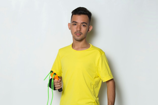 Young handsome sport man holding skipping rope on white background