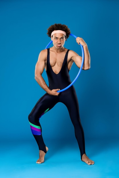 Young handsome sportive african man posing with hoop on blue