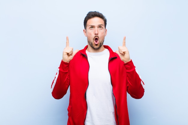 Young handsome sports man or monitor feeling awed and open mouthed pointing upwards 