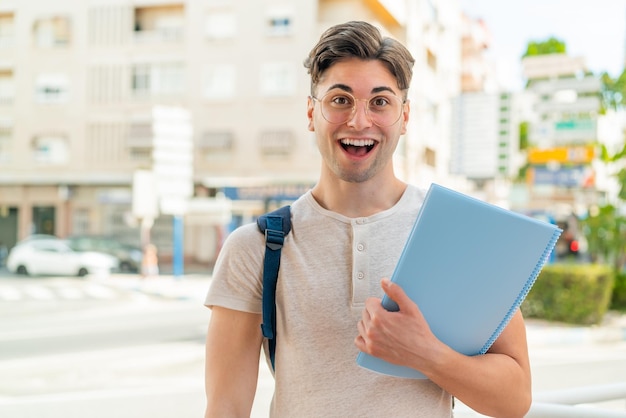 驚きとショックを受けた表情で屋外で若いハンサムな学生男性