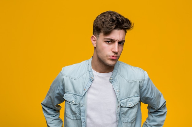 Young handsome student wearing a denim shirt scolding someone very angry.