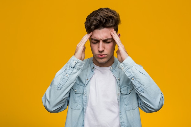 Young handsome student wearing a denim shirt touching temples and having headache.