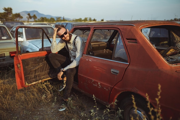 Young handsome stylish man wearing shirt and bowtie with old cars