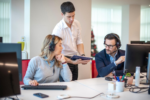 Young handsome supervisor bringing and showing performance review to his employees at call center
