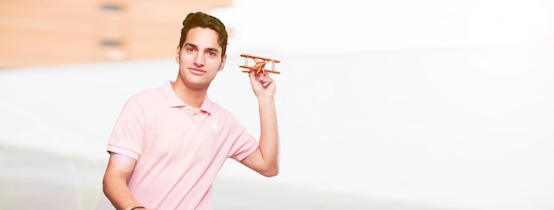 Young handsome tanned man with a wooden plane