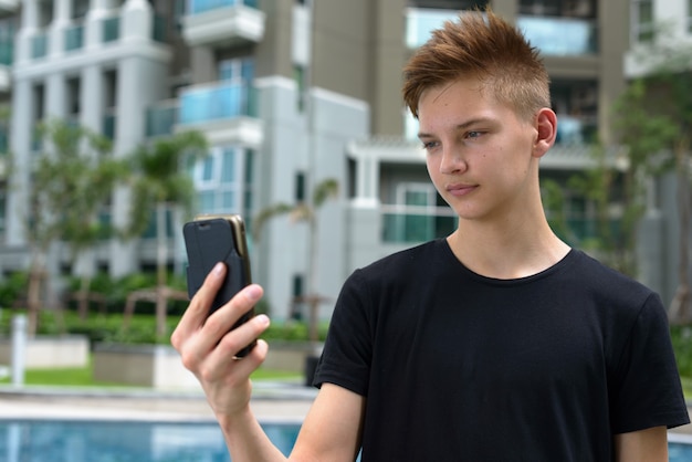 Young handsome teenage boy with blond hair outdoors