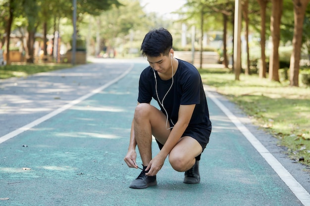 写真 公園で音楽を聴いて屋外で運動している若いハンサムなタイ人男性。テキスト用のコピースペース
