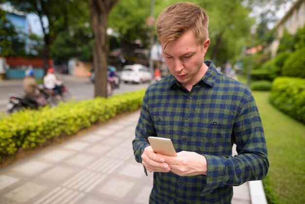 Young handsome tourist man using mobile phone in Vietnam