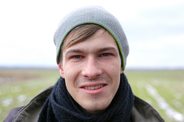 Young handsome unshaven guy close-up face portrait on a spring field background with green grass.