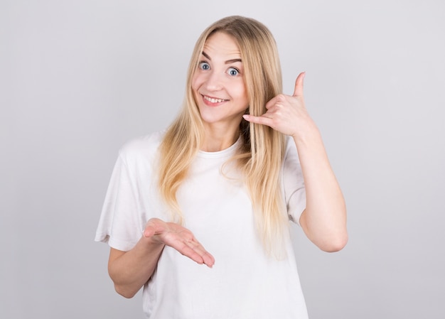 Young handsome woman smiling doing phone gesture with hand and fingers like talking on the telephone.