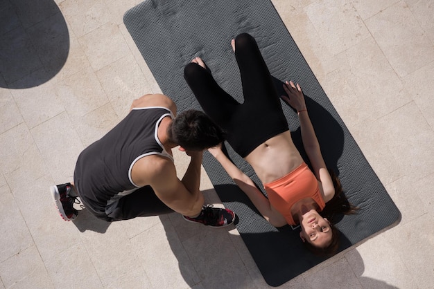 young handsome woman with personal trainer doing morning yoga exercises in front of her luxury home villa top view