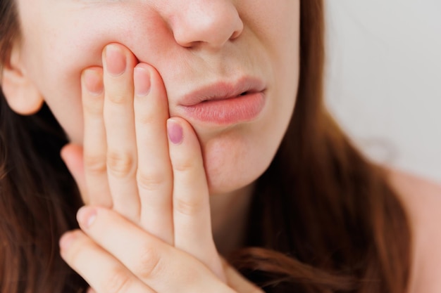 Giovane bella giovane donna espressione di orribile soffre di mal di denti in piedi sopra il bianco isolato