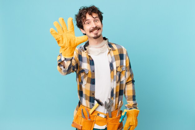 Young handyman housekeeper smiling and looking friendly, showing number five