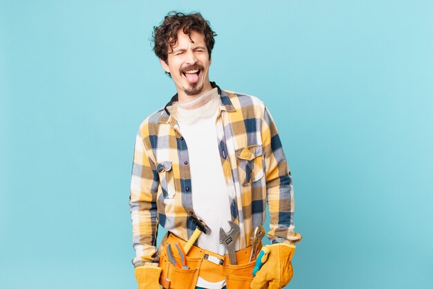 Young handyman housekeeper with cheerful and rebellious attitude, joking and sticking tongue out