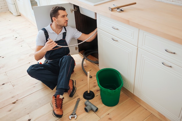 Young handyman sit on floor in kitchen