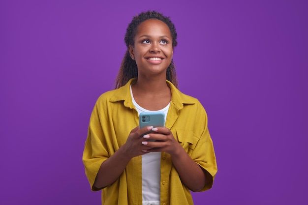 Young happy african american woman smiling broadly looking up using phone