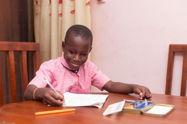 Young Happy African school boy smiling writing on book