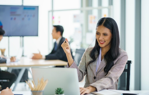 Giovane donna di affari asiatica felice che lavora e usa un computer portatile e un'idea di pensiero per la sua attività