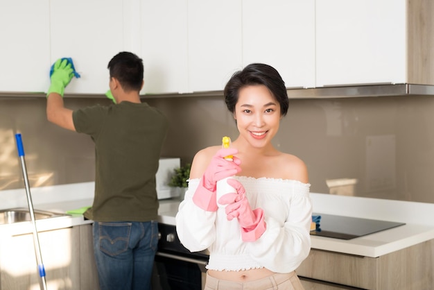 Young happy Asian couple is having fun while doing cleaning at home