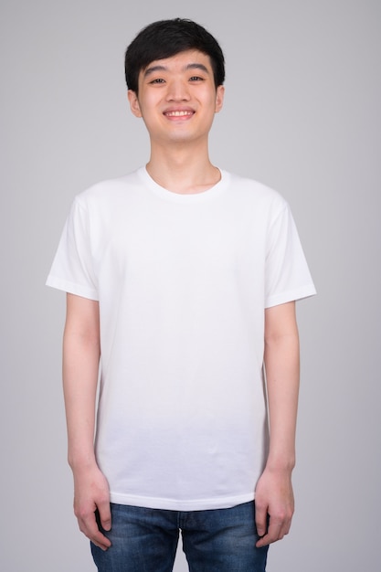 young happy Asian man smiling and standing