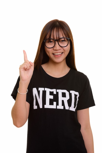 Young happy Asian nerd teenage girl smiling and pointing finger