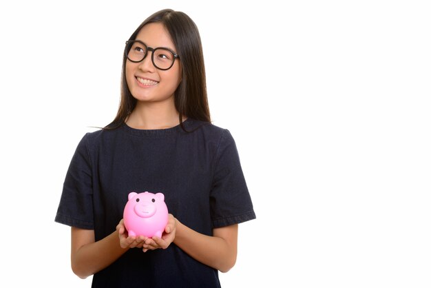 Giovane adolescente asiatico felice che sorride e che tiene banca piggy