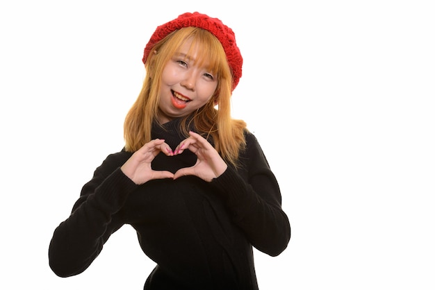 웃 고 손 심장 기호를 만드는 젊은 행복 한 아시아 여자