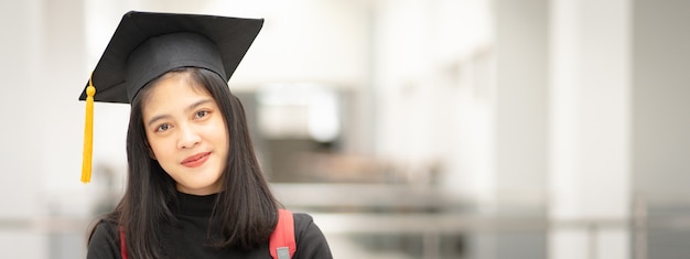 대학 캠퍼스에서 졸업 가운과 모자를 쓴 젊은 행복한 아시아 여성 대학 졸업. 교육 스톡 사진