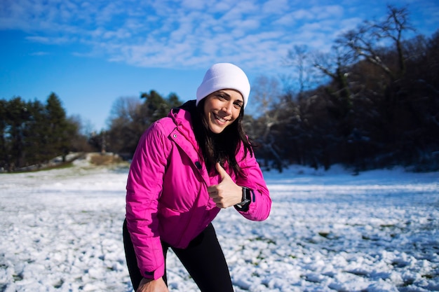 Young happy athlete showing thumbs up in mountains on snow, winter day.