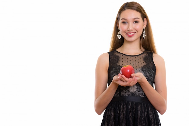 Молодая счастливая красивая азиатская женщина улыбается, держа красное яблоко