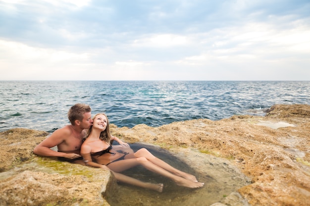 Young happy beautiful couple woman and man enjoying time in natural rock pool with water