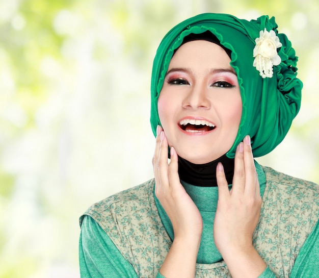 ヒジャーブを着ている緑の衣装で若い幸せな美しいイスラム教徒の女性