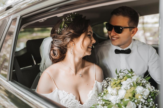 Photo young happy bride and groom are rejoicing after the wedding ceremony in their car