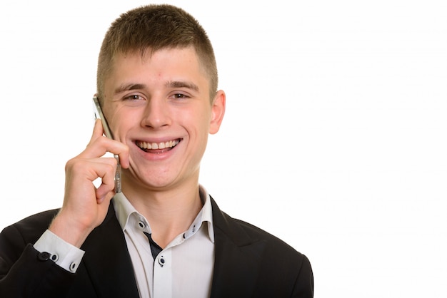 молодой счастливый бизнесмен улыбается и разговаривает по мобильному телефону