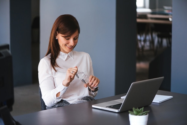 Young happy businesswoman holding a bottle of water in office