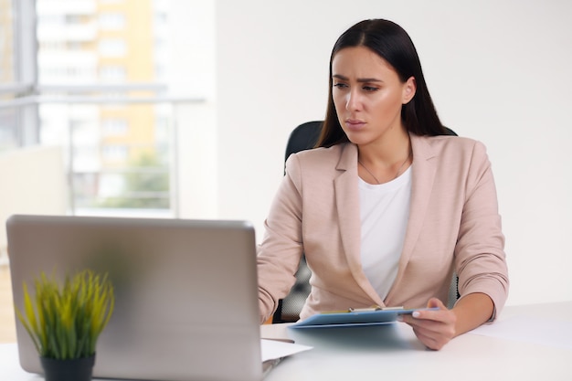 Young happy businesswoman in the office, making notes in a notebook