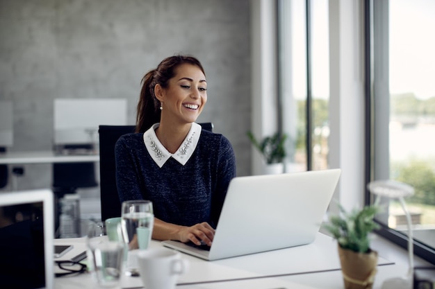 Photo young happy businesswoman working on laptop in the office