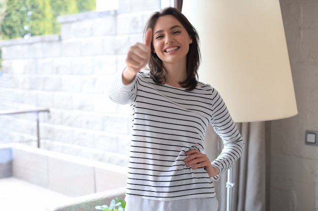 Young happy cheerful woman showing thumb up.