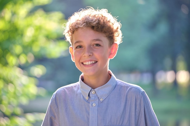 Young happy child boy relaxing in summer park Positive kid enjoying summertime outdoors Child wellbeing concept