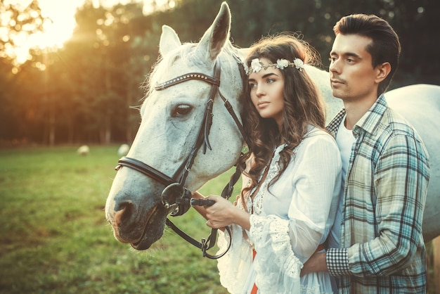 Young happy couple and beautiful horse