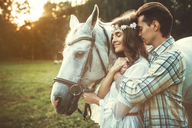 若い幸せなカップルと美しい馬