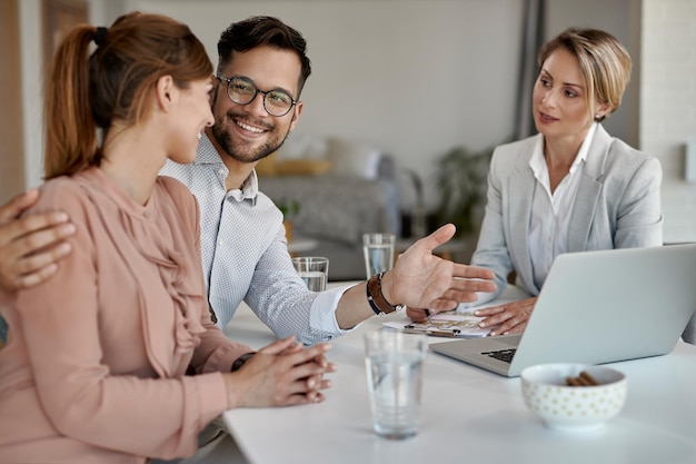 Young happy couple communicating while being on a meeting with their real estate agent