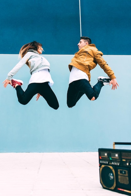 Young happy couple dancing on the street with a vintage radio cassette stereo