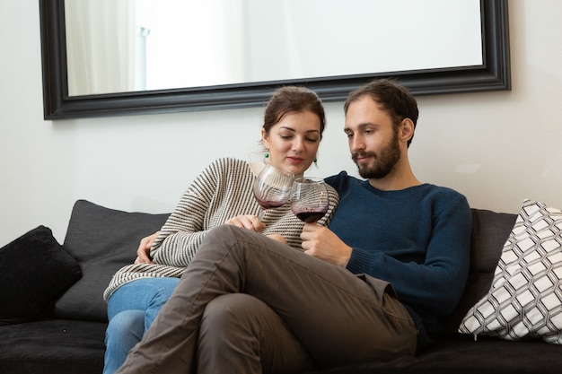 Young and happy couple drinking wine and relaxing at home