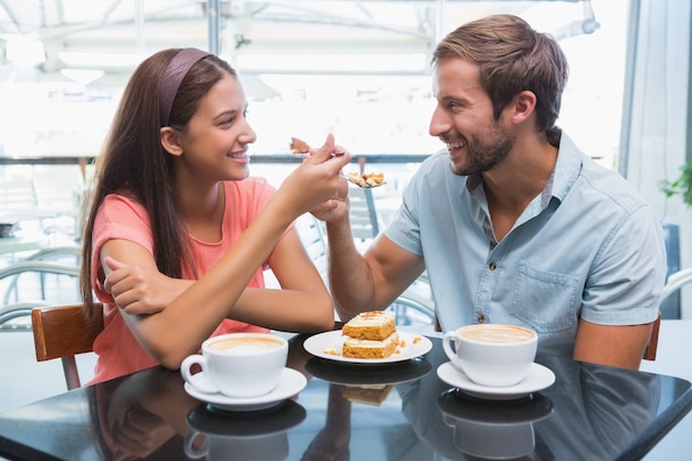 Photo young happy couple eating cake together