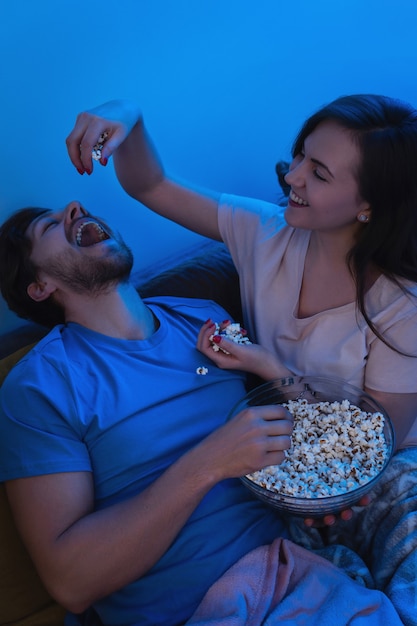 Photo young and happy couple eating popcorn and watching movie