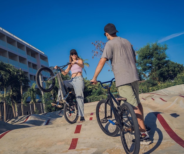 若い幸せなカップルは、スケートパークで BMX に乗って楽しむ