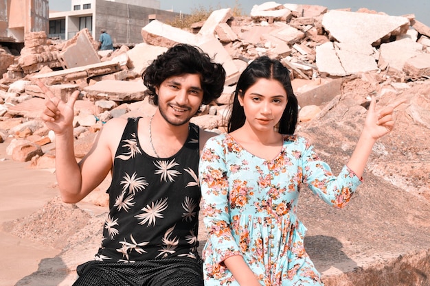 молодая счастливая пара позирует спереди, указывая в сторону на пляж, индийская пакистанская модель
